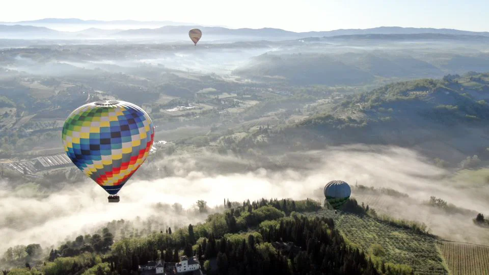 hot air balloons over misty tuscan valley