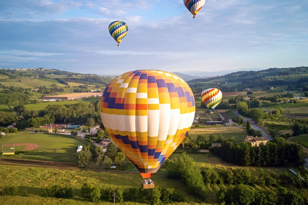 Hot air balloons floating over green countryside at sunrise, flight from Siena in Tuscany